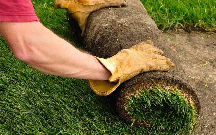 turf being rolled out by person in yellow gloves