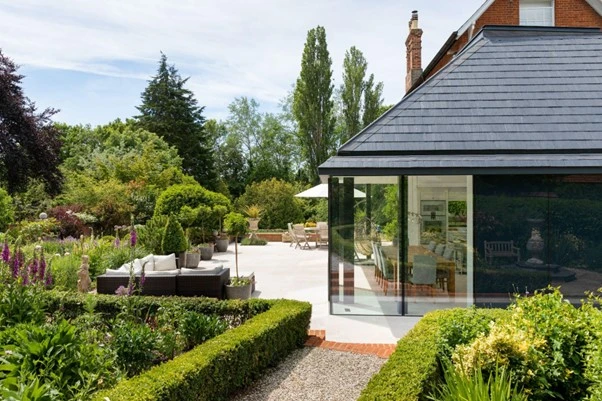 A modern kitchen enjoys views of the garden through floor-to-ceiling glazing.