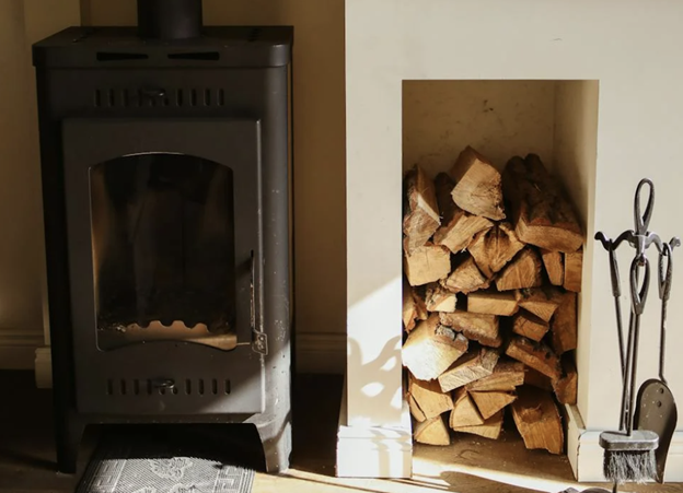 black Wood burning stove with wood stacked in storage hole in wall