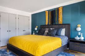Artistic yellow and blue bedroom. Blue feature wall with yellow accents with blue pillow and yellow duvet cover