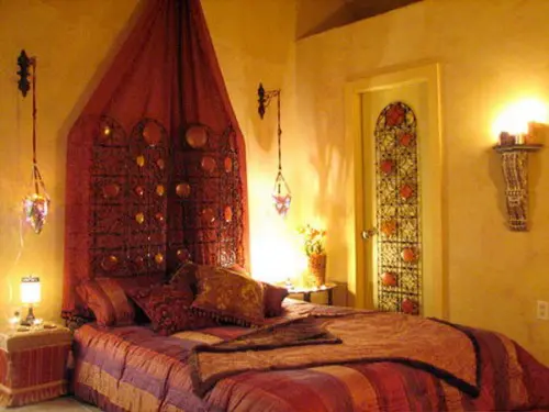 Moroccan style bedroom with orange and red bedding with yellow walls